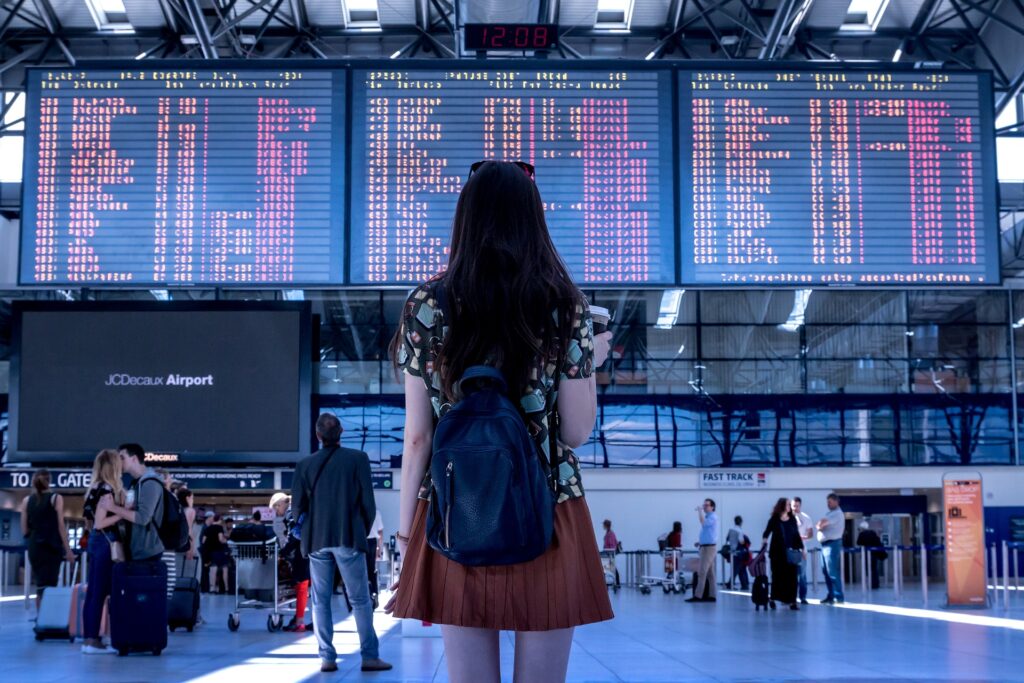 Frau steht am Flughafen vor grosser Abflugstafel
