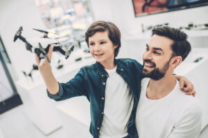 Vater trägt Dohn auf dem Arm, Sohn hat Drone in der Hand